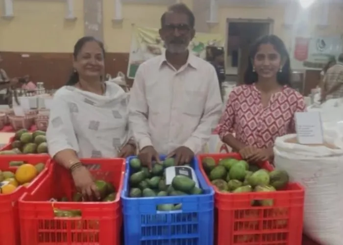 Anarghya with her parents behind crates of mangoes at their stall