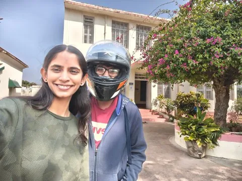 A selfie, him still in his helmet, outside an old building with bougainvillea