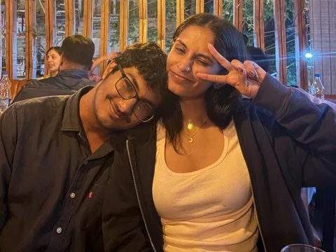 His head on her shoulder at a cafe, her flashing a peace sign