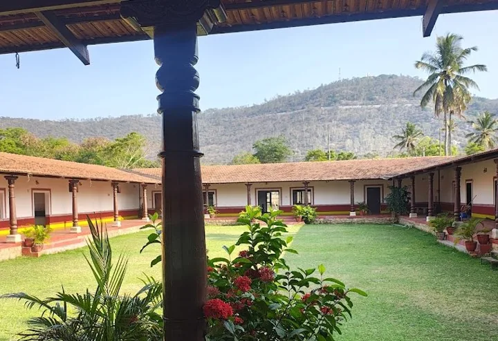 The courtyard at Angala: a green lawn ringed by a tiled verandah with wooden pillars, hills behind